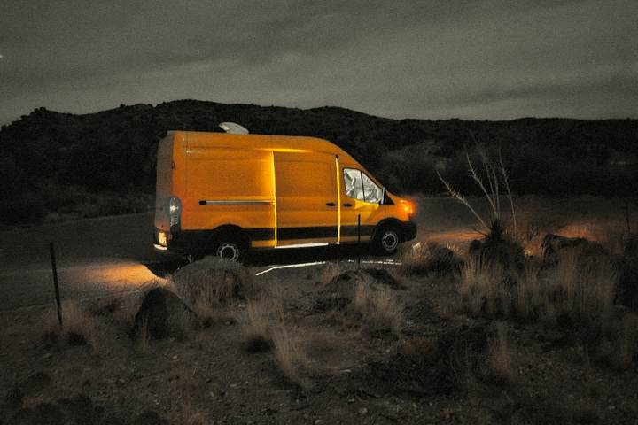 The van at dusk on a desert pull-off with headlights on