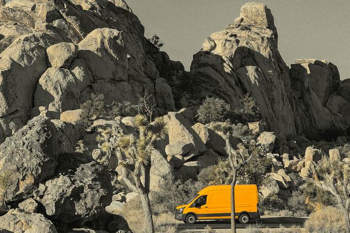 Yellow Transit parked below granite boulders in Joshua Tree