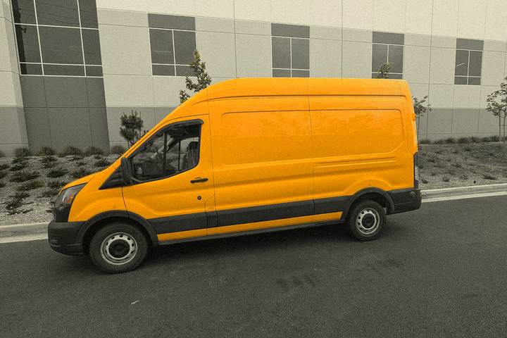 Driver-side profile of the van against a warehouse wall